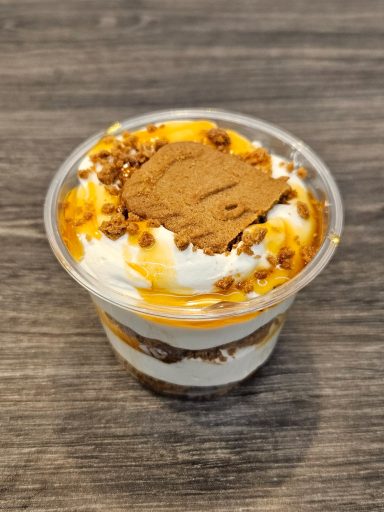 Dessert en coupe avec crème, sauce caramel et miettes de biscuit.